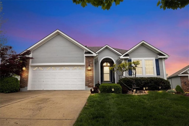 ranch-style home featuring a lawn, driveway, brick siding, and a garage