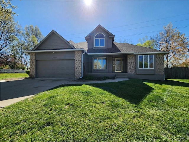 traditional home featuring concrete driveway, a front lawn, brick siding, a garage, and fence