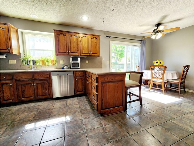 kitchen featuring a breakfast bar area, a peninsula, dishwasher, and a textured ceiling