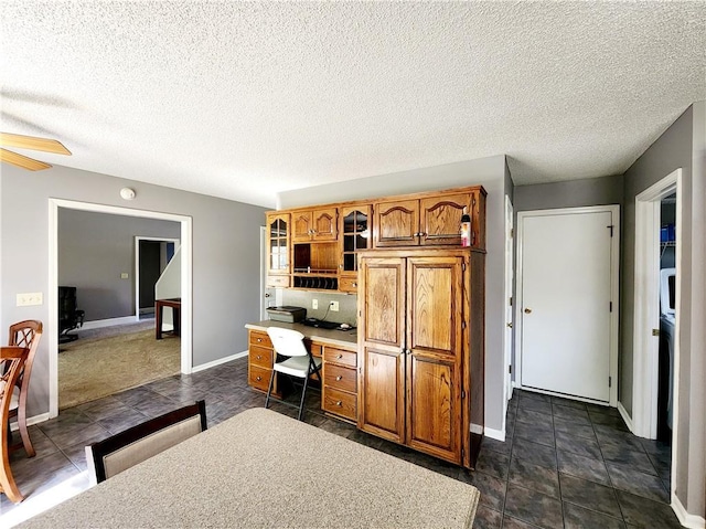 interior space with brown cabinets, ceiling fan, baseboards, and glass insert cabinets