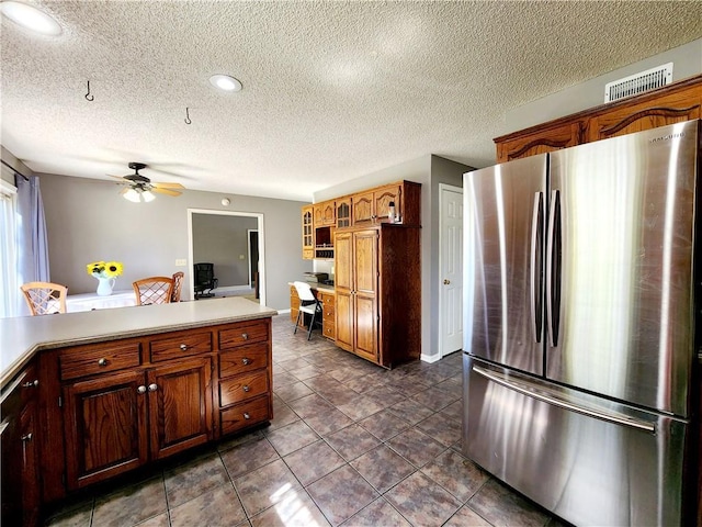 kitchen featuring glass insert cabinets, a textured ceiling, light countertops, freestanding refrigerator, and ceiling fan