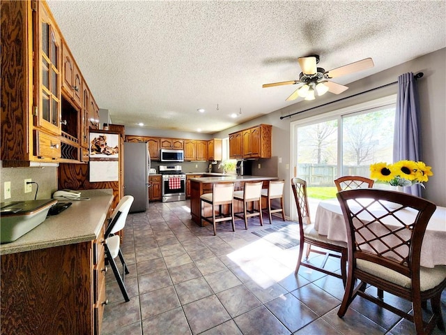 tiled dining room with a ceiling fan, recessed lighting, and a textured ceiling