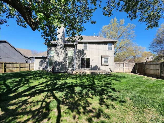 rear view of property with a patio area, a fenced backyard, a lawn, and a chimney