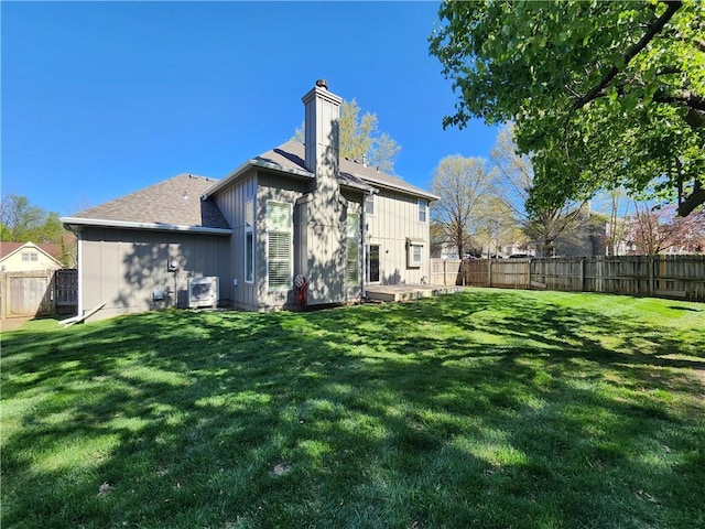 back of house with a yard, a fenced backyard, and a chimney