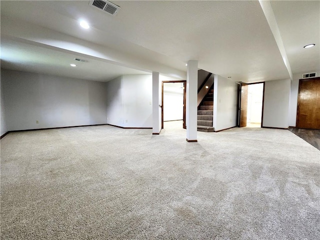finished below grade area featuring visible vents, baseboards, carpet flooring, and stairs