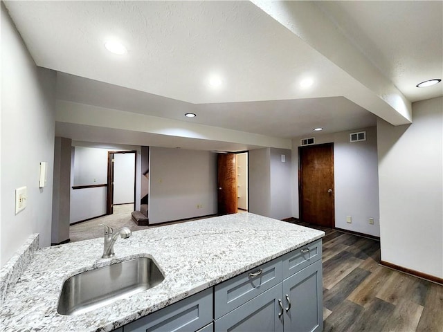 kitchen with gray cabinets, recessed lighting, visible vents, a sink, and wood finished floors