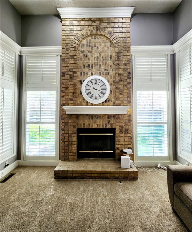 carpeted living area featuring a brick fireplace and visible vents