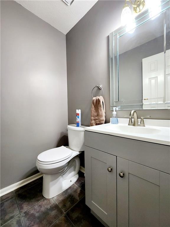half bath with tile patterned floors, toilet, vanity, and baseboards