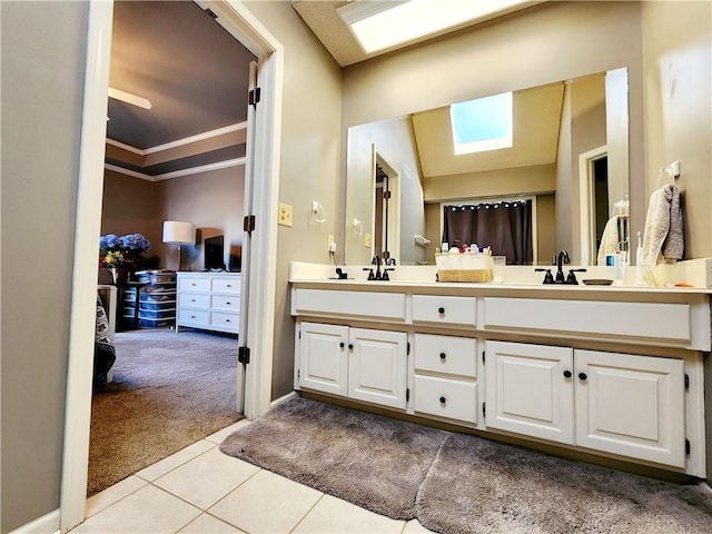 bathroom with ornamental molding, tile patterned flooring, a skylight, a sink, and double vanity