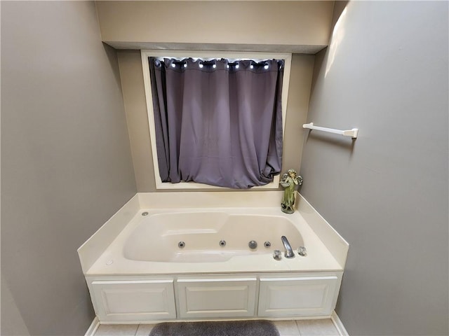 bathroom with tile patterned floors, baseboards, and a tub with jets