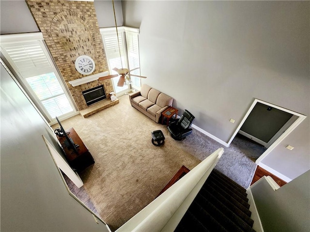 carpeted living room featuring baseboards, ceiling fan, and a fireplace