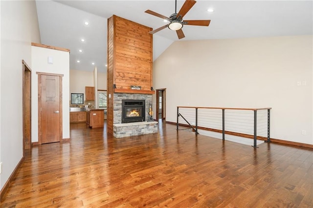 unfurnished living room with baseboards, a ceiling fan, wood finished floors, and high vaulted ceiling
