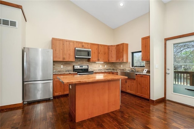 kitchen featuring backsplash, visible vents, butcher block countertops, appliances with stainless steel finishes, and high vaulted ceiling