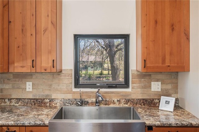 kitchen featuring dark stone countertops, decorative backsplash, and a sink