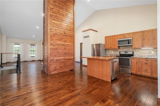 kitchen featuring stainless steel appliances, dark wood-style floors, visible vents, high vaulted ceiling, and a kitchen island