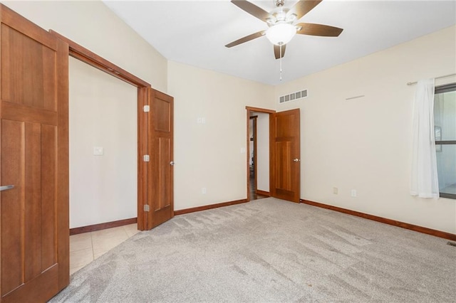unfurnished bedroom with tile patterned floors, carpet flooring, visible vents, baseboards, and a ceiling fan