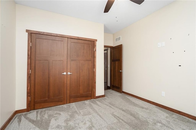 unfurnished bedroom featuring a ceiling fan, a closet, light colored carpet, baseboards, and visible vents