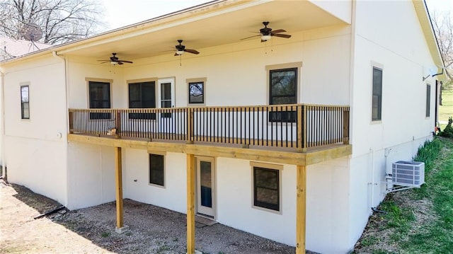 back of property with a ceiling fan, central air condition unit, and stucco siding