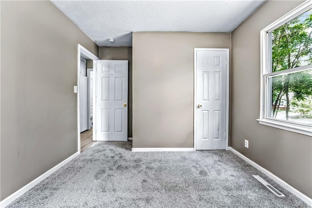 unfurnished bedroom featuring carpet, baseboards, and a textured ceiling
