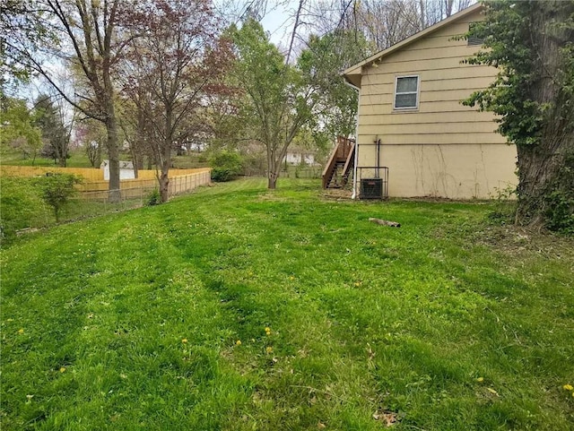 view of yard featuring fence, stairs, and central AC unit