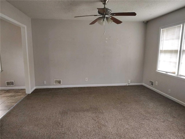 carpeted spare room featuring baseboards, visible vents, a textured ceiling, and ceiling fan