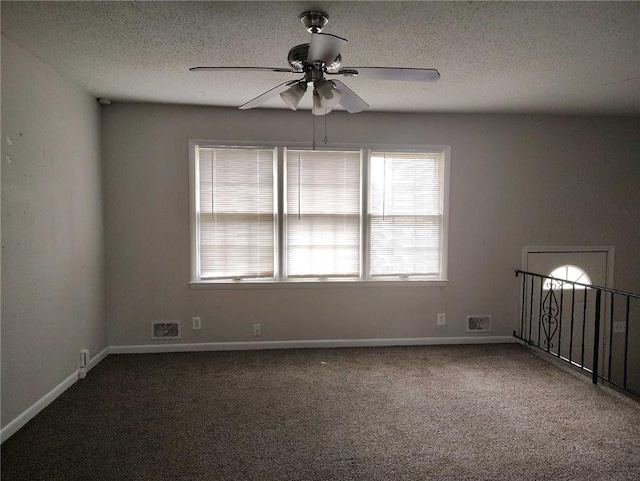 carpeted spare room with visible vents, a ceiling fan, baseboards, and a textured ceiling