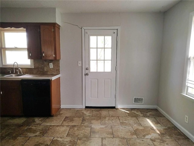 kitchen with a sink, baseboards, black dishwasher, decorative backsplash, and light countertops