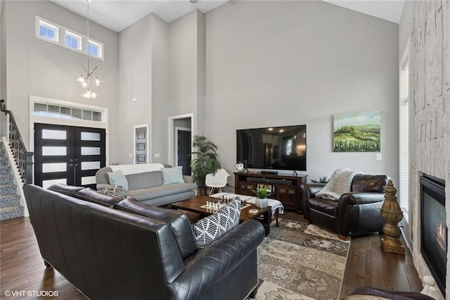 living room featuring french doors, stairway, high vaulted ceiling, a chandelier, and hardwood / wood-style floors