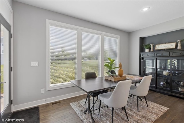 dining area with wood-type flooring, baseboards, visible vents, and plenty of natural light