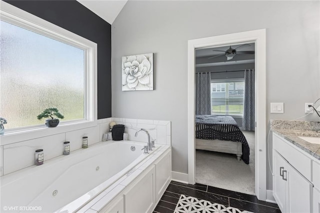 ensuite bathroom with tile patterned flooring, a ceiling fan, baseboards, a tub with jets, and lofted ceiling