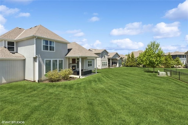 rear view of house with roof with shingles, a lawn, a patio area, fence, and an outdoor hangout area