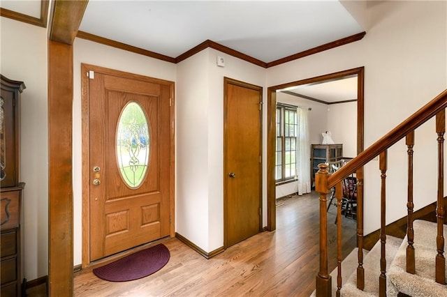 foyer entrance featuring wood finished floors, stairway, ornamental molding, baseboards, and a fireplace