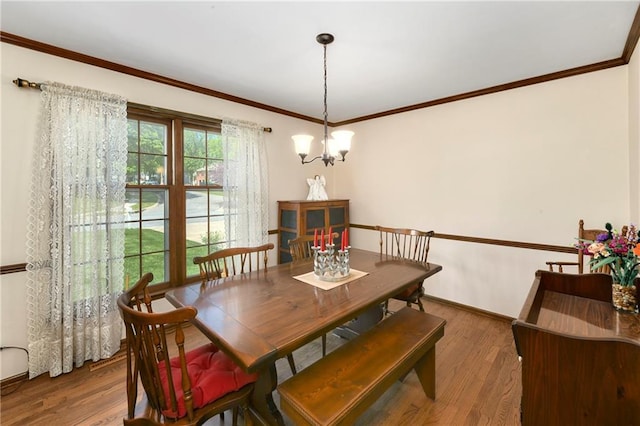 dining room featuring wood finished floors, a chandelier, crown molding, and baseboards