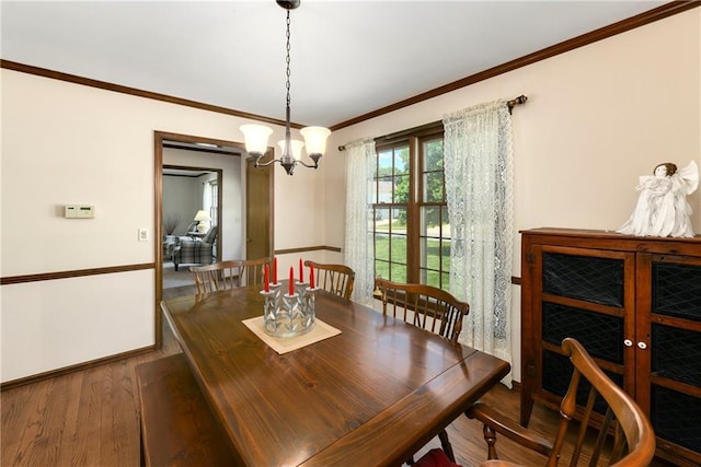 dining area featuring ornamental molding, a chandelier, and wood finished floors