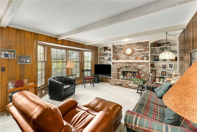 living area featuring beamed ceiling, carpet flooring, wooden walls, and a brick fireplace