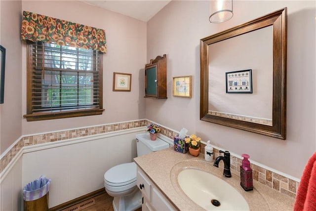 bathroom featuring wainscoting, toilet, and vanity