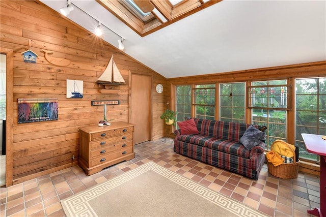 living room with a skylight, lofted ceiling, track lighting, and wood walls
