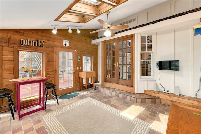 interior space featuring wooden walls, french doors, lofted ceiling, a ceiling fan, and track lighting