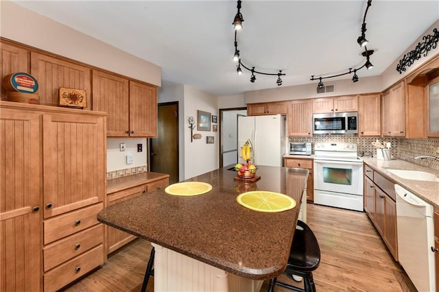 kitchen with white appliances, a sink, a kitchen bar, and backsplash