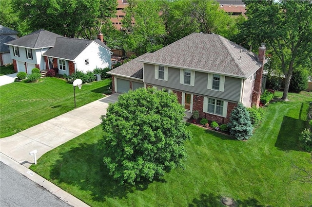 colonial-style house with brick siding, concrete driveway, a front yard, a chimney, and an attached garage