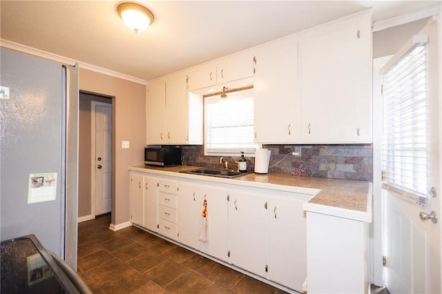 kitchen featuring decorative backsplash, black microwave, a sink, and white cabinets