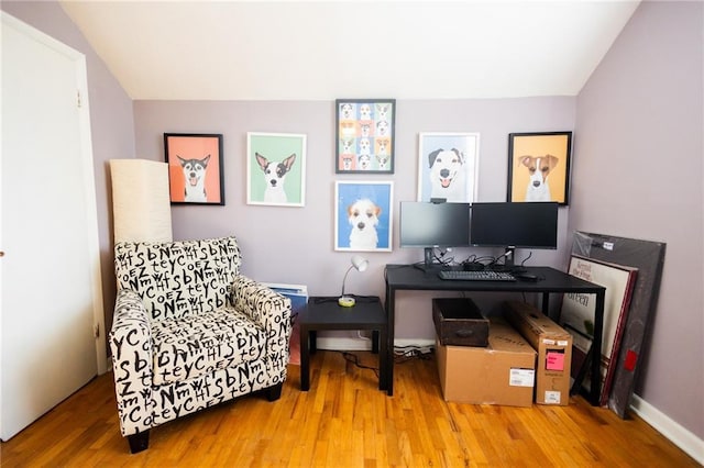 office space featuring lofted ceiling, baseboards, and wood finished floors