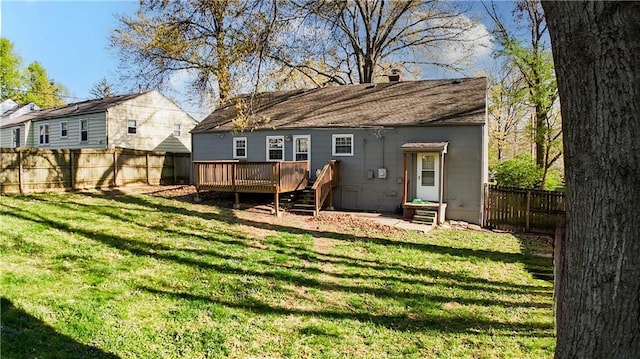 back of property with a lawn, a wooden deck, and a fenced backyard