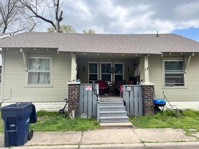 view of front facade featuring roof with shingles and a porch