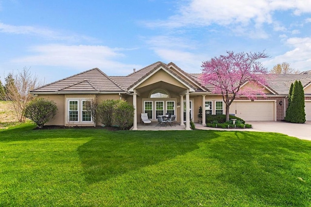 view of front facade featuring concrete driveway, an attached garage, a front lawn, stucco siding, and a tile roof