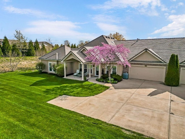 view of front of home featuring a tiled roof, concrete driveway, an attached garage, a front yard, and stucco siding