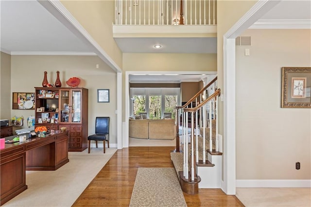 entryway featuring stairs, baseboards, wood finished floors, visible vents, and ornamental molding