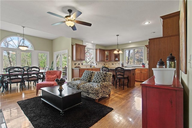 living area with plenty of natural light, light wood finished floors, and ceiling fan
