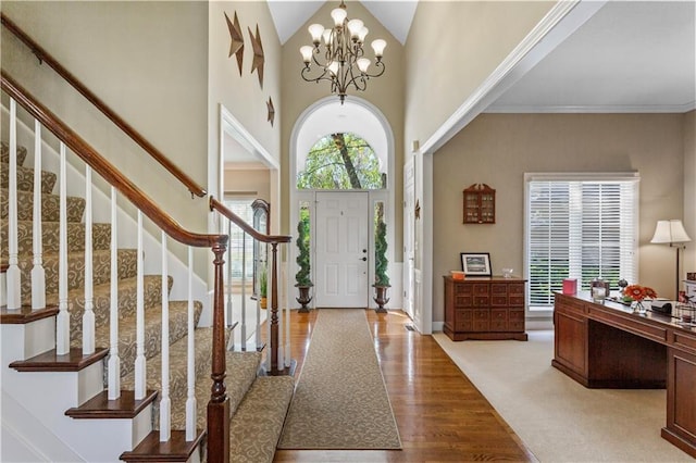 entryway featuring a high ceiling, a notable chandelier, wood finished floors, and stairway