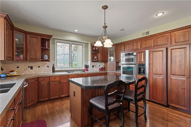 kitchen featuring brown cabinetry, open shelves, a kitchen breakfast bar, backsplash, and stainless steel appliances